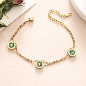 Detail of gold double-layer chain bracelet with green circular pendants and zircon inlay