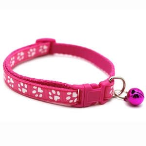 Close-up of pink pet collar featuring white paw prints with a buckle and purple bell