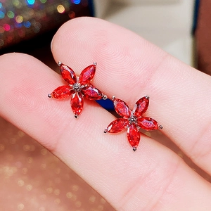 Macro detail of silver floral stud earrings featuring five vibrant red marquise-cut stones