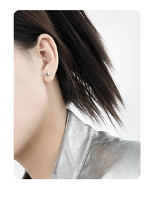 Close-up of a minimalist silver heart stud earring worn on a model's earlobe