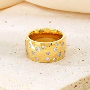 Macro shot of gold-plated titanium ring with sparkling zircons on a stone surface