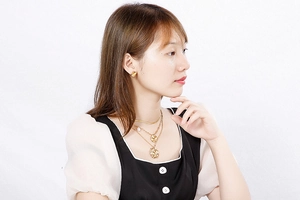Close-up of model wearing multi-layer gold geometric necklace and round earrings set