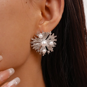 Close-up of silver geometric flower earrings with white pearls on female model