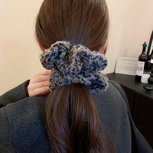 Détail de la texture d'un chouchou en tweed bleu et marron à paillettes sur une queue