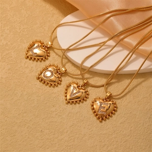 Detail of four gold heart pendants with L-O-V-E letters and sparkling zircon stones