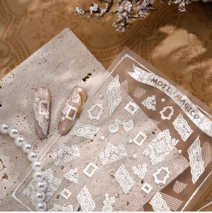 Detail of vintage white lace nail stickers with embossed pearl and crown patterns