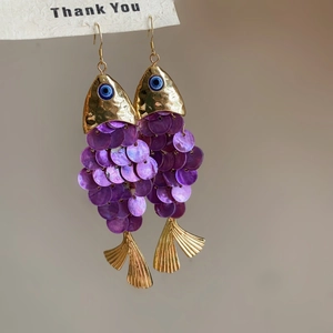 Ethnic fish earrings with purple sequins and evil eye detail on a gold hook