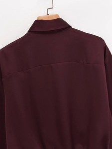 Detail view of the back collar and silky dark red fabric texture on a wooden hanger