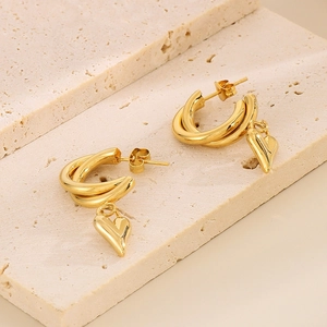 Detailed macro view of gold-plated double-loop hoop earrings with heart pendants