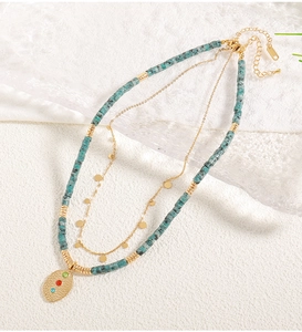 Detail of bohemian layered necklace with green stone beads and hammered gold pendant