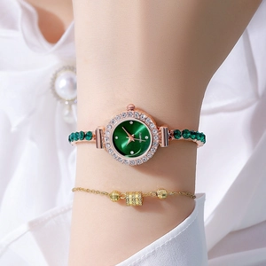 Macro view of women's gold-tone watch with green dial and gemstone-set link bracelet