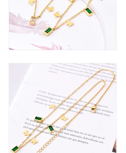 Detail of gold butterfly necklace featuring rectangular green and white gemstones