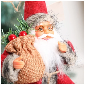 Close-up of plush Santa gnome with knitted red hat, white beard, and small gift bag