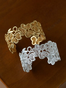 Detailed macro of gold and silver filigree flower bangles on a vintage wood texture