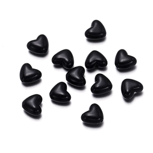 Macro detail of glossy black heart-shaped acrylic beads with pre-drilled holes for DIY jewelry