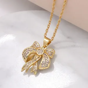 Elegante ciondolo a fiocco dorato con zirconi brillanti su sfondo di marmo bianco