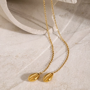 Close-up of elegant shell pendant on gold stainless steel chain with stone backdrop