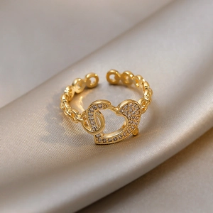 Detailed shot of golden heart-shaped rhinestone ring with chain band on silk