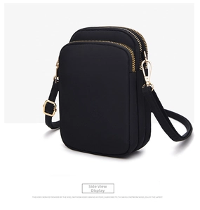Close-up of a black nylon crossbody phone bag with three layered gold zipper pockets
