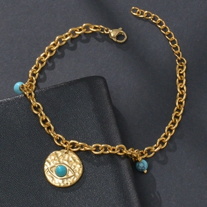 Detailed view of the gold chain bracelet with turquoise evil eye charm and vintage beads