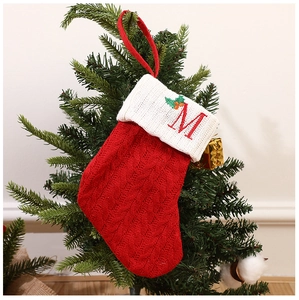 Close-up of a red knitted Christmas stocking with white cuff and letter M embroidery