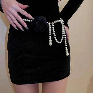 Detail einer mehrreihigen Perlen-Taillenkette mit schwarzer Stoffblume am schwarzen Kleid