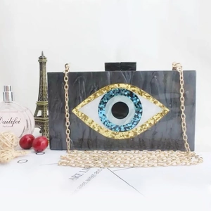Detailed macro of Evil Eye acrylic clutch with marble texture and golden chain strap