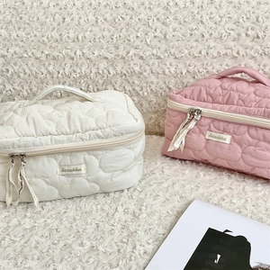Detail of pink and white quilted cosmetic bags with heart patterns and ribbon zippers