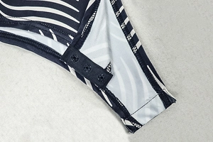 Detail of snap button closure and wavy stripe print on blue and white bodysuit