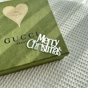 Close-up of silver Merry Christmas acrylic cake topper on a green decorative gift box