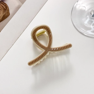 Detail of a small striped hair claw clip in cream and brown with a metal spring mechanism