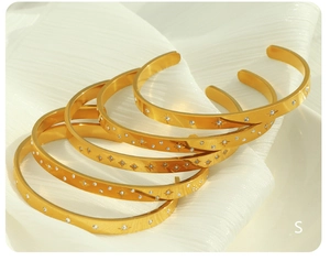 Detailed macro view of 18K gold plated steel bangles with star pattern and zircon inlay
