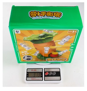 Carrot balance tower game packaging and components on scale weighing 313g