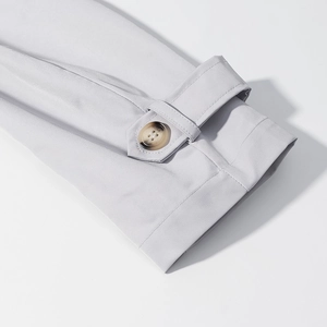 Detail of light gray blazer sleeve featuring a cuff strap with a tortoiseshell button