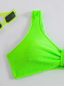 Detail of neon green smocked fabric texture on a stylish bikini top with matching sunglasses