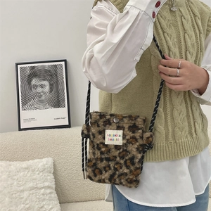 Detail of leopard print faux fur crossbody bag with woven strap and magnetic closure