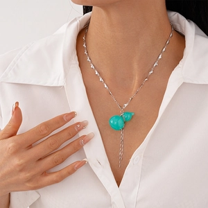 Détail du pendentif gourde en résine verte avec pompons et chaîne à maillons cœur argent