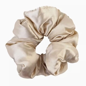 Detailed view of large champagne satin hair scrunchie with soft silk texture and glossy finish