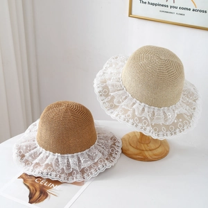 Close-up of woven straw sun hat featuring delicate white lace trim and natural texture