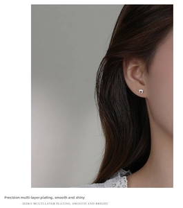 Close-up of minimalist silver cat paw stud earrings worn by a model in a side view