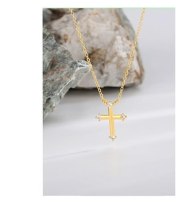 Macro shot of minimalist gold cross necklace with four embedded zircon stones on rocky base