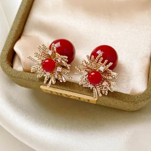 Elegant gold flower earrings with red pearls and zircon accents on green velvet