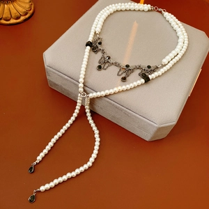 Detailed macro of vintage pearl tassel necklace with black teardrop pendant on box