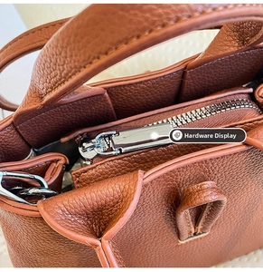 Detailed close-up of silver metal zipper and brown lychee grain leather stitching