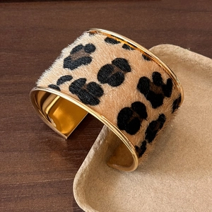 Détail du bracelet manchette léopard en velours avec bords dorés sur bois