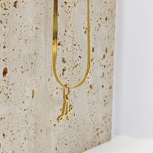 Close-up of golden letter A pendant with heart detail on flat snake chain necklace