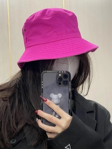 Close-up of a pink fluorescent bucket hat worn by a model in a mirrored selfie view