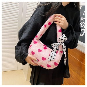 Close-up of pink fuzzy handbag with heart patterns and polka dot ribbon detail