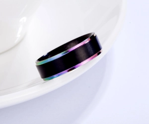 Macro shot of matte black titanium ring with rainbow edge on white ceramic detail
