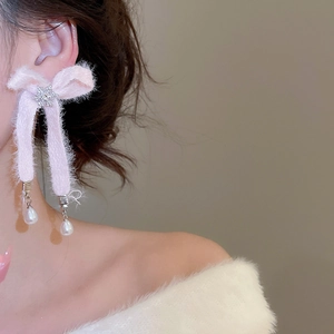 Close-up of pink plush bow earrings with snowflake detail and dangling pearls